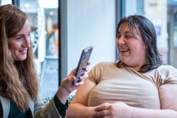 Two ladies looking at a phone and smiling