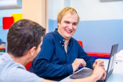 Happy mental disabled man and teacher in IT class